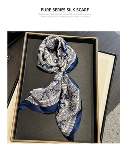 Gros plan d'un foulard en soie bleu marine à motifs paisley et boucle en perle