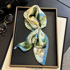 Close-up of elegant silk scarf with scenic print and a pearl metal buckle accessory