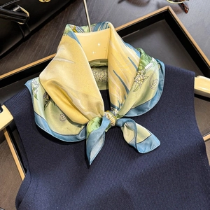 Detailed close-up of a premium yellow and blue silk scarf tied on a navy knit top