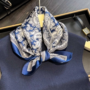 Foulard élégant en soie bleu marine à motif paisley stylisé sur un haut en tricot chic