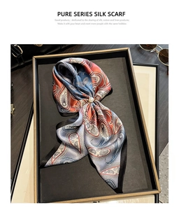 Detail of paisley silk scarf folded as a bow with a pearl buckle in a luxury display