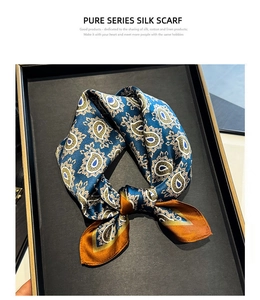 Detail of luxury silk square scarf with blue paisley pattern on a black matte tray