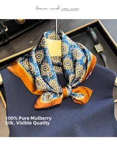 Detail of 100% mulberry silk scarf with blue and orange paisley pattern on a knit sweater