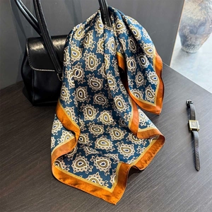 Elegant mulberry silk scarf with blue paisley pattern and orange borders on handbag