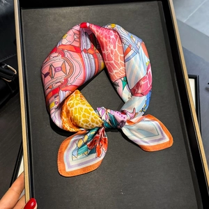 Artistic silk scarf featuring bright giraffe and castle prints on a black display tray
