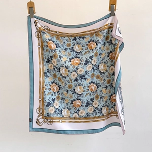 Light blue square silk scarf featuring yellow roses and equestrian belt prints on a hanger