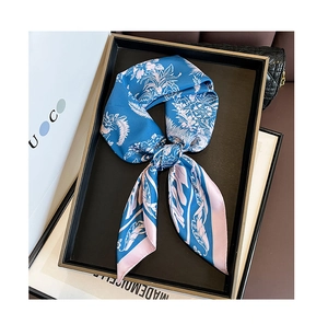 Detailed close-up of blue silk scarf with pink feather print tied in a neat bow