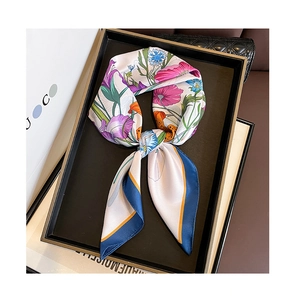 Detail of floral print silk scarf with iris patterns and navy border on a display tray