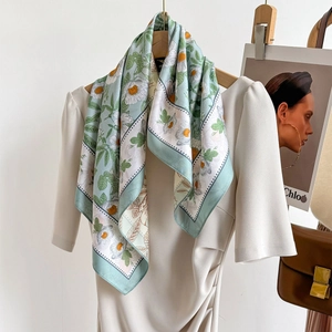 Foulard en soie vert menthe à fleurs de marguerites noué sur une robe crème