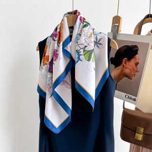 Floral print silk scarf with blue border styled on black outfit for an elegant look