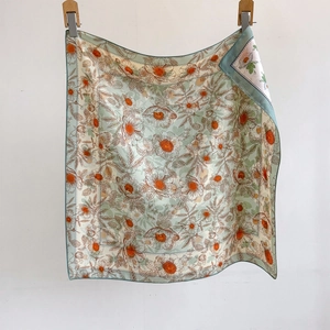 Carré de soie vert sauge avec motifs marguerites oranges suspendu à des pinces