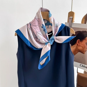 Floral silk scarf with pink and blue prints and navy borders styled on a neckline