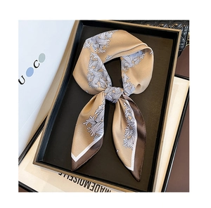 Détail d'un foulard en soie or champagne avec motif ondulé sur un plateau chic