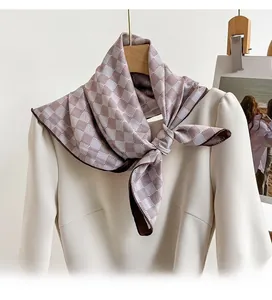 Détail d'un foulard en soie à carreaux café porté sur une robe blanche élégante