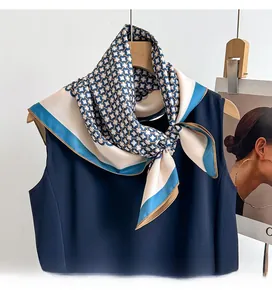 Detailed shot of twill silk scarf with blue geometric chain patterns tied on a navy dress