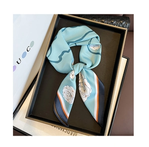 Detail of silk twill scarf featuring camellia print and contrast borders in a luxury tray