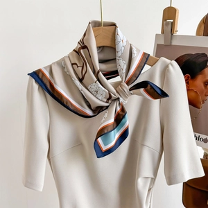 Elegant floral silk scarf with geometric stripe border styled on a beige dress