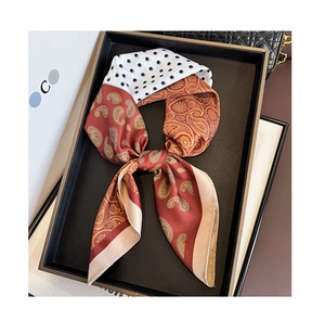 Macro detail of red paisley and polka dot twill silk scarf tied in an elegant bow
