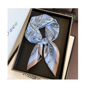 Detail of light blue paisley silk scarf tied in a tray next to fashion accessories