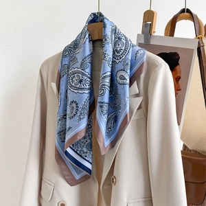 Blue paisley silk scarf draped on a beige blazer for an elegant and fashionable style