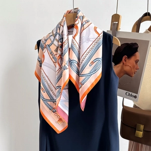 Detail view of double-sided chain print silk scarf draped on a navy blue sleeveless dress