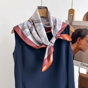 Detail of vintage luxury silk scarf with gold chain and crest patterns on a blue dress