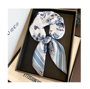 Close-up of elegant floral silk scarf with blue patterns tied in a bow on a tray