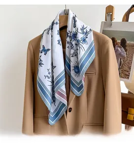 Detail of floral silk scarf with blue butterfly pattern styled on a camel blazer