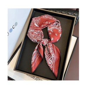 Detail of red paisley silk scarf with black piping edges tied in a bow on a display tray