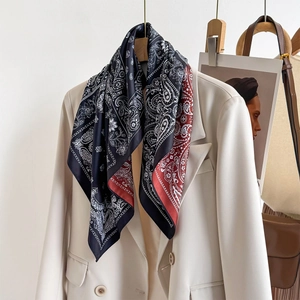 Vintage paisley pattern silk scarf in black and burgundy draped on a beige blazer