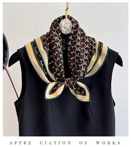 Close-up of geometric pattern silk scarf with green stitched edges and retro interlocking print
