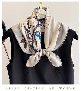 Detail of silk wool scarf with floral print and black border tied on a black dress