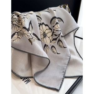 Macro shot of light grey silk wool scarf featuring floral prints and herringbone texture