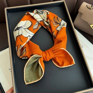 Detailed view of silk wool scarf with orange floral pattern and herringbone texture