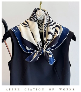 Close-up of zebra pattern silk wool scarf with a white camellia brooch and blue trim