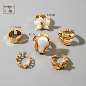 6-piece gold ring set with irregular pearls and hollow designs on a grey background