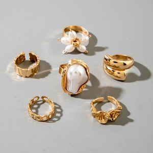 Detail of 6pcs gold flower and baroque pearl rings with hammered and lava texture finish