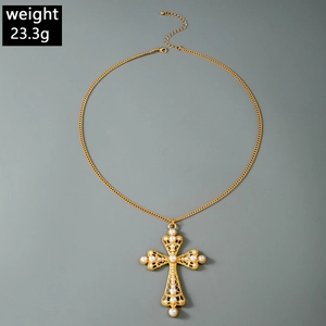 Détail d'un collier croix doré vintage avec incrustations de perles et travail du métal
