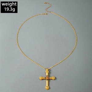Gros plan d'un pendentif croix dorée vintage avec pierres colorées, pesant 19,3 grammes
