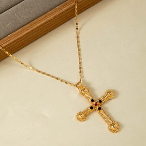 Gros plan détaillé du pendentif croix dorée vintage avec pierres rouges et noires