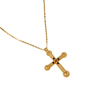 Collier croix multicouche vintage doré avec pierre rouge et perles sur fond blanc