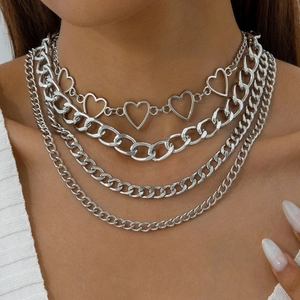 Close-up of layered silver chain necklace with hollow heart and Cuban links on model