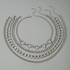 Detail of silver multilayer necklace set with hollow heart charms and cuban chains