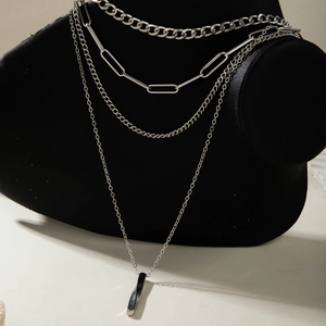 Detail of layered silver metal necklaces with chunky Cuban chains and geometric pendants