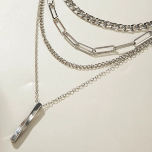 Close-up of multilayer silver chain necklace featuring chunky cuban and paperclip links