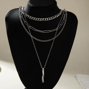 Detail of multi-layered silver chains including Cuban link, paperclip chain and bar pendant
