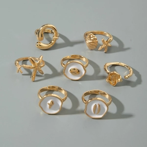 Flat lay of gold ocean themed ring set featuring starfish and shell designs with white enamel