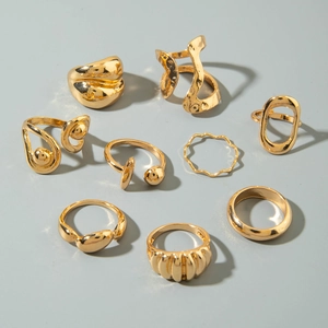 Flat lay of 9 gold geometric open rings featuring irregular and wave minimalist designs