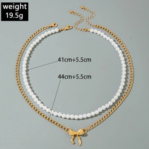 Détail d'un collier double rang avec perles, pendentif nœud doré et mesures de taille