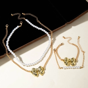 Détail du collier de perles double couche et bracelet avec nœuds dorés sur présentoir